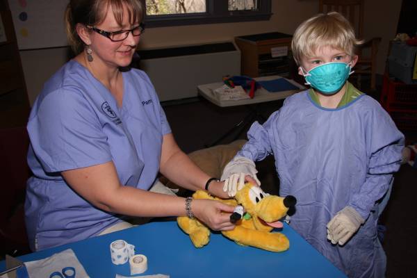 Veterinary worker and a kid playing doctor with a stuffed toy